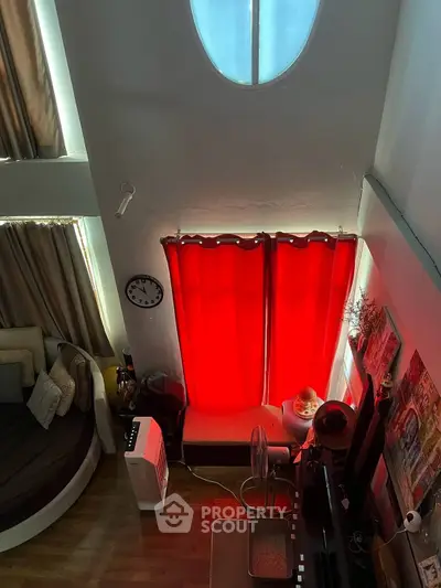 Cozy living room with unique circular window and vibrant red curtains