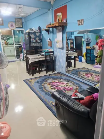 Cozy living room with elegant rugs and dining area in a vibrant blue setting.