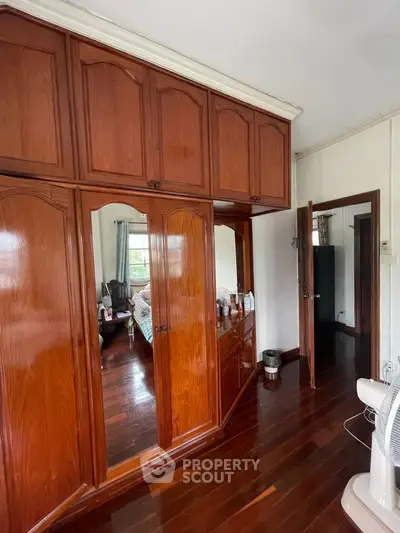 Spacious bedroom with wooden wardrobes and polished floors, offering ample storage and natural light.