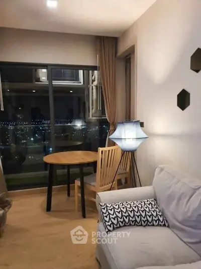 Cozy living room with city view, featuring modern furniture and ambient lighting.