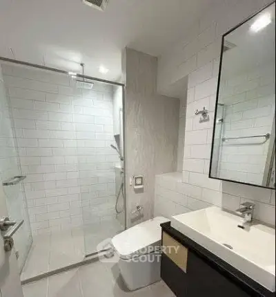 Modern bathroom with glass shower and sleek fixtures in contemporary apartment.