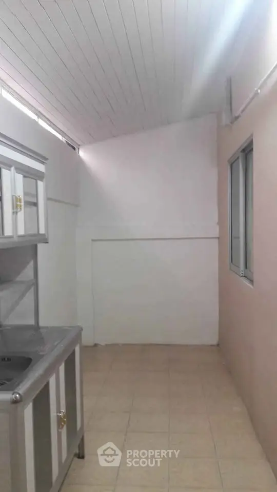 Compact kitchen area with tiled floor and stainless steel sink, ideal for small apartments.