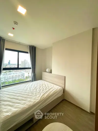 Bright bedroom with large window offering city view, modern furnishings, and cozy ambiance.