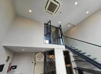 Modern loft apartment with high ceilings and sleek staircase, featuring an open layout and stylish design.