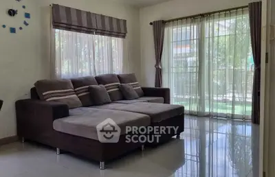 Spacious living room with large windows and modern sofa, offering a bright and inviting atmosphere.
