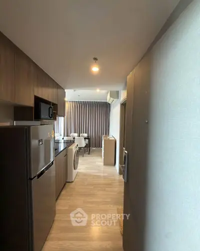 Modern kitchen with sleek appliances and open layout leading to dining area.