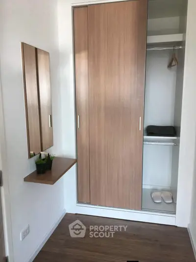 Modern minimalist wardrobe with mirror and wooden flooring in a cozy bedroom corner.
