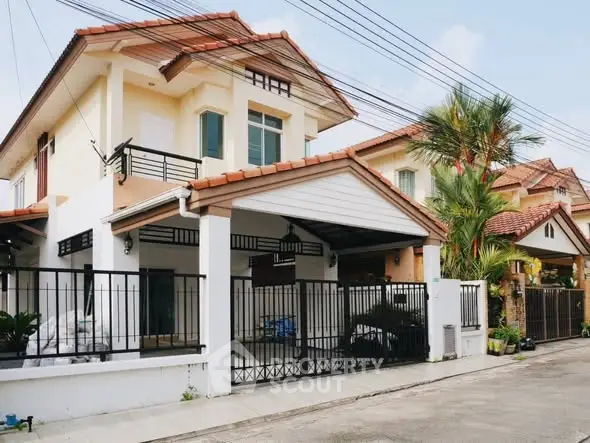 Charming two-story house with gated entrance and tiled roof in a suburban neighborhood.