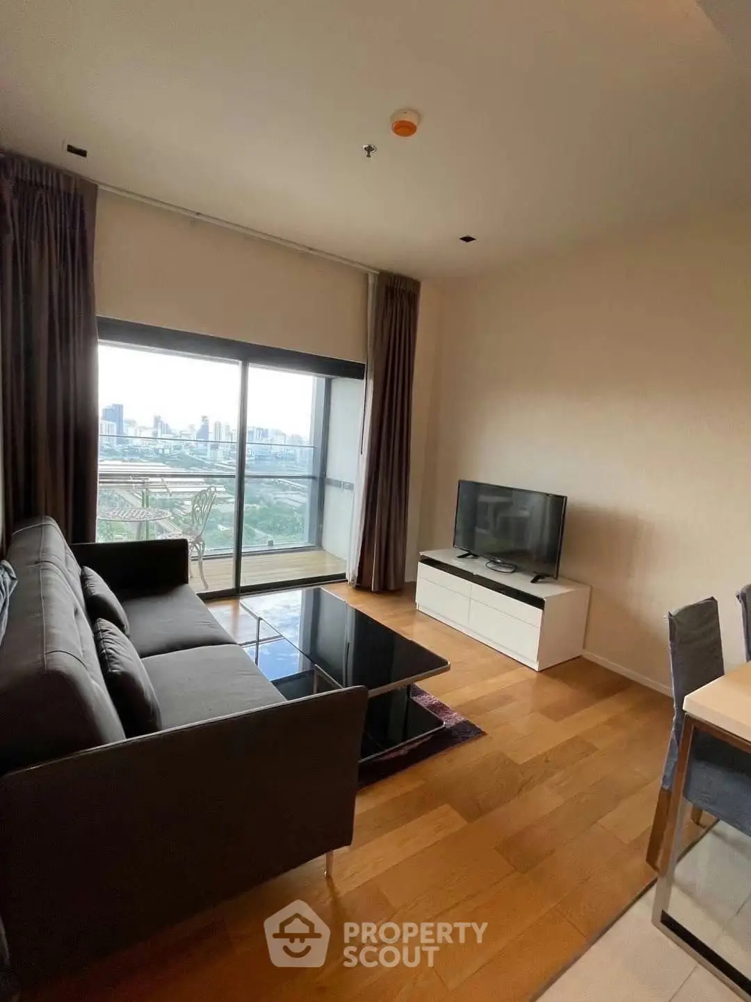 Modern living room with city view, featuring sleek furniture and large windows for natural light.