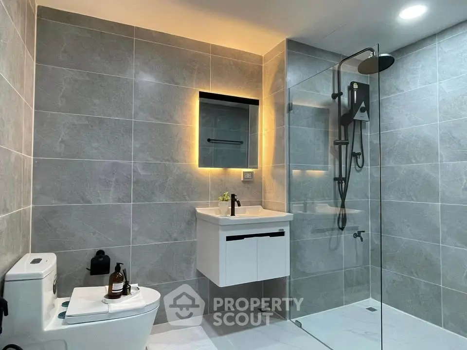 Modern bathroom with sleek design, featuring a glass shower and elegant lighting.
