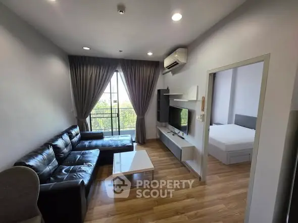 Modern living room with sleek furniture and natural light, featuring a cozy bedroom view.