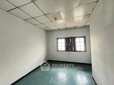 Spacious empty room with tiled ceiling and large windows, perfect for customization.