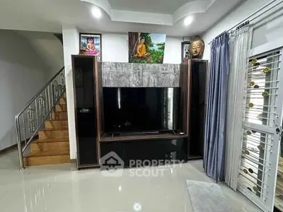 Modern living room with sleek TV unit and elegant staircase in a stylish home interior.