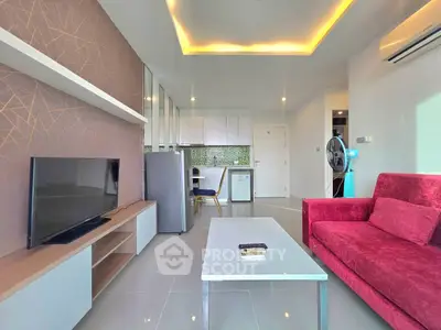 Modern living room with stylish decor, featuring a red sofa, sleek TV unit, and open kitchen layout.