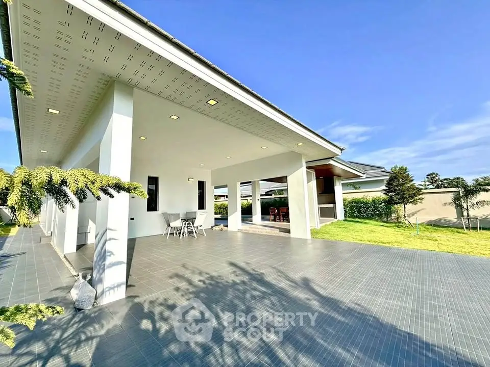 Spacious modern patio with tiled flooring and lush green lawn in a contemporary home.