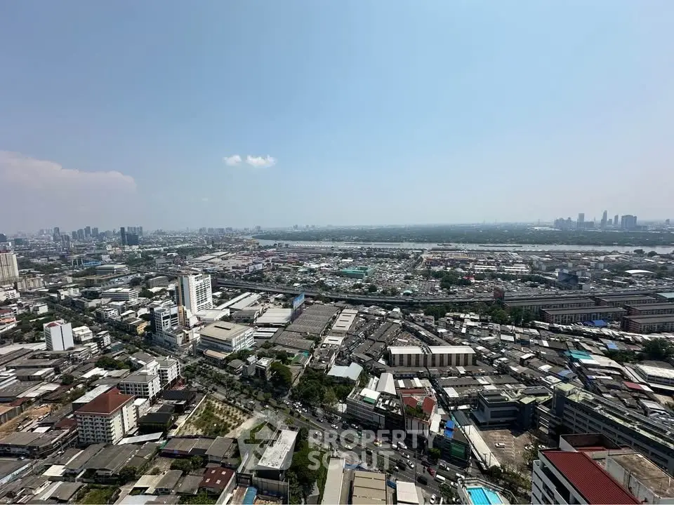 Stunning panoramic cityscape view from high-rise building, showcasing urban skyline and river in the distance.