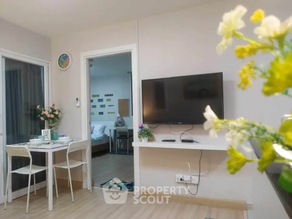 Modern living room with wall-mounted TV and dining area in cozy apartment.