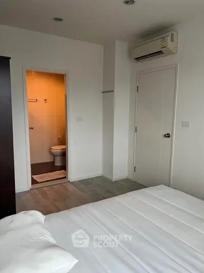 Cozy bedroom with ensuite bathroom and air conditioning in modern apartment.