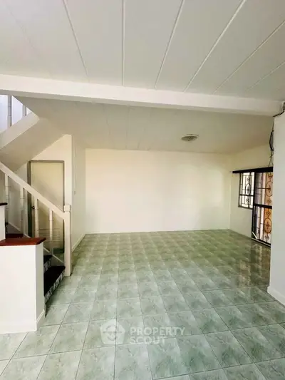 Spacious living room with tiled flooring and staircase in modern home