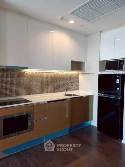 Modern kitchen with sleek cabinetry, built-in appliances, and stylish backsplash in a contemporary apartment.
