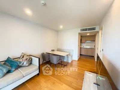 Modern living room with wooden flooring and open kitchen layout in a stylish apartment.