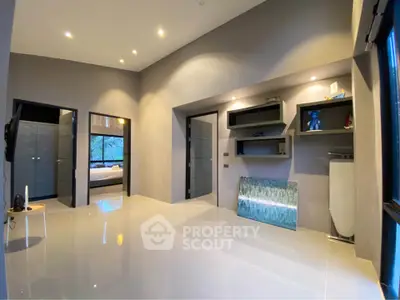 Modern living room with sleek design and recessed lighting, featuring glossy floors and contemporary shelving.