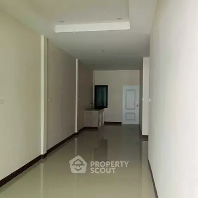 Spacious empty room with glossy tiled floor and recessed ceiling lights, ideal for customization.