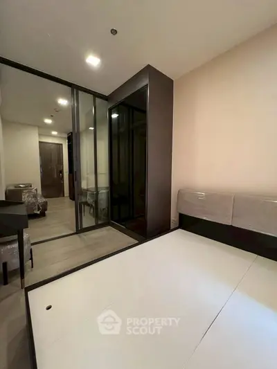 Modern bedroom with sleek design and mirrored wardrobe in a stylish apartment.