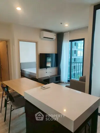 Modern open-plan living room with sleek kitchen island and large windows offering natural light.