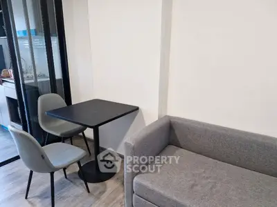 Modern living room with cozy gray sofa and dining area in open layout apartment.