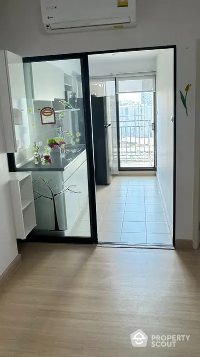 Modern kitchen with sliding glass door leading to a balcony with city view.