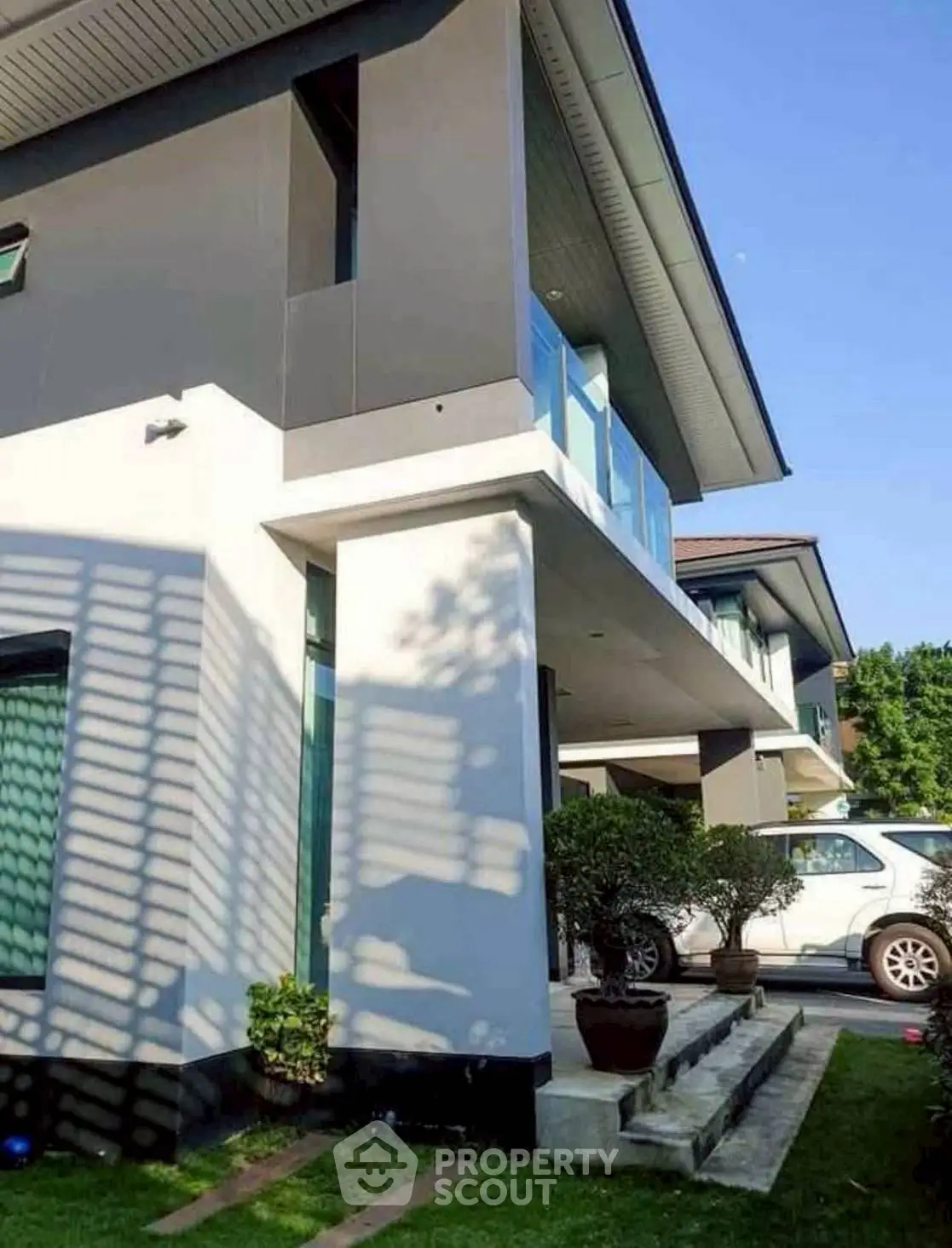 Modern two-story house with sleek design and lush greenery