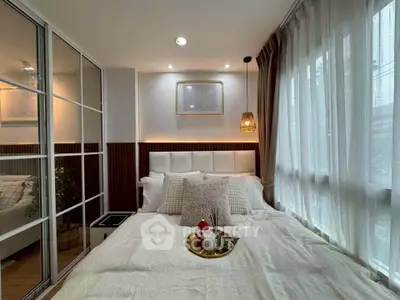 Cozy bedroom with modern decor and large window for natural light.