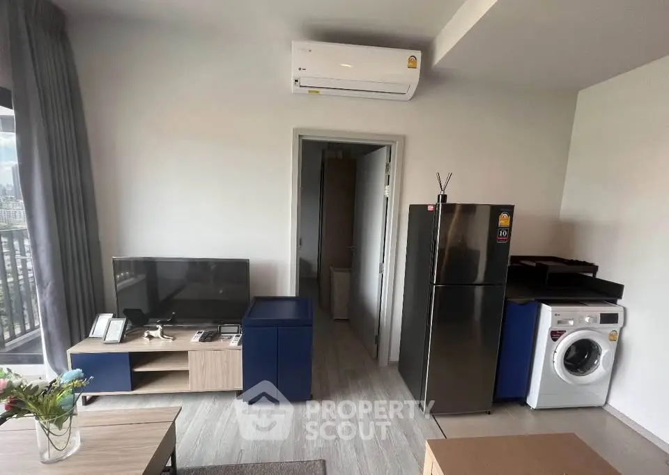 Modern living room with balcony, featuring sleek furniture, air conditioning, and in-unit washer and fridge.