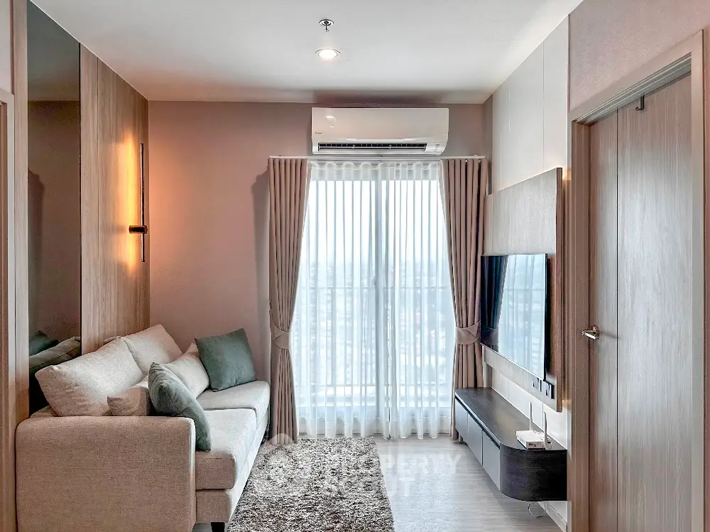 Modern living room with cozy sofa, wall-mounted TV, and large window with city view.