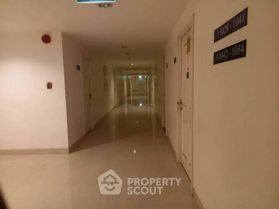 Spacious hotel corridor with polished floors and room number signs.
