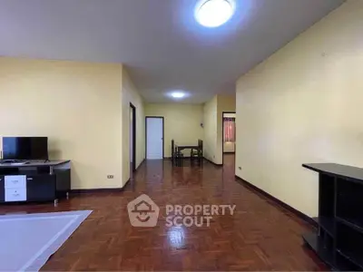 Spacious living room with wooden flooring and modern furniture in a cozy apartment.