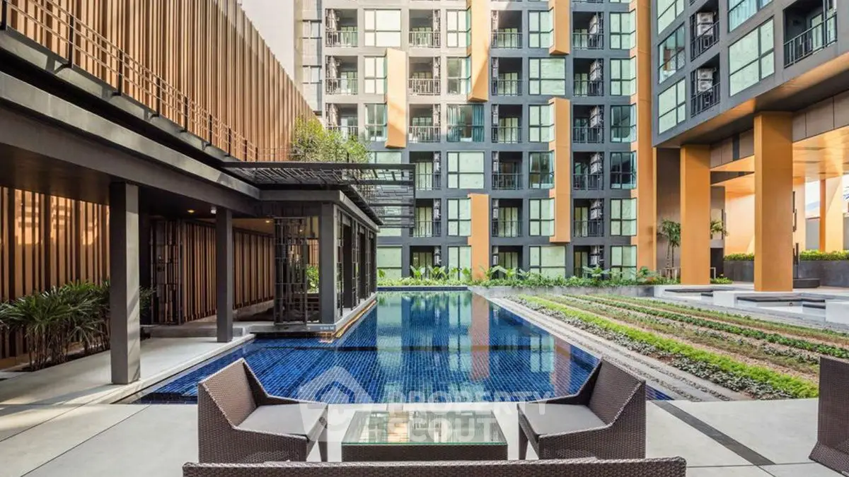 Luxurious modern apartment complex with stunning pool and stylish outdoor seating area.