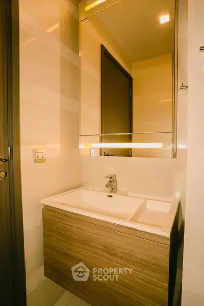 Modern bathroom with sleek wooden vanity and illuminated mirror