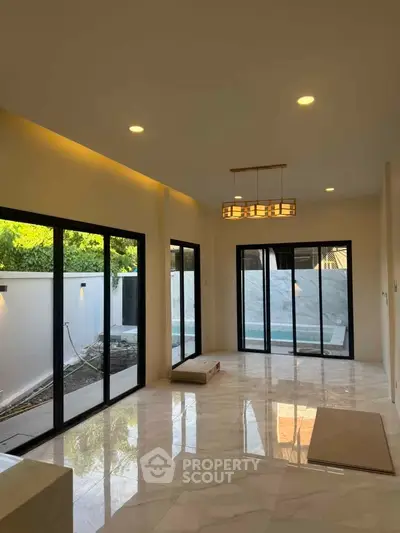 Spacious modern living room with large windows and pool view, perfect for relaxation and entertainment.