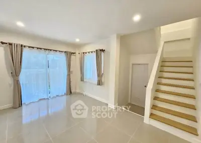 Spacious living room with elegant staircase and large windows for natural light