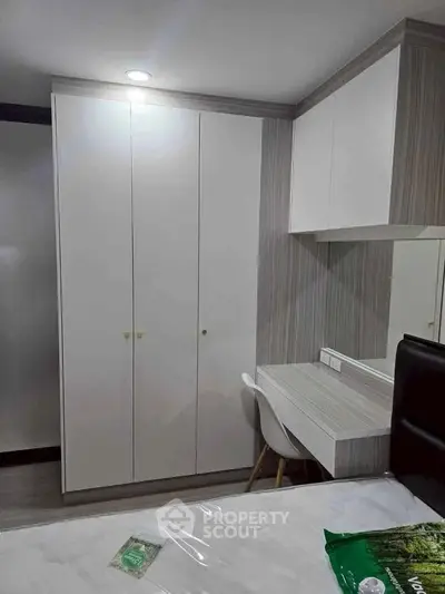 Modern bedroom with sleek wardrobe and stylish study desk in a cozy apartment.