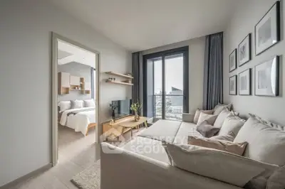 Modern living room with large windows and cozy seating, adjacent to a stylish bedroom.