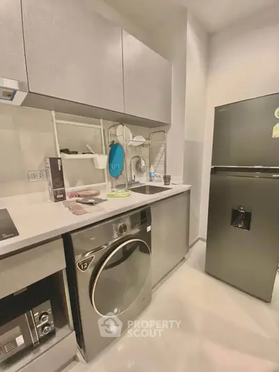 Modern kitchen with sleek appliances and washing machine in compact layout