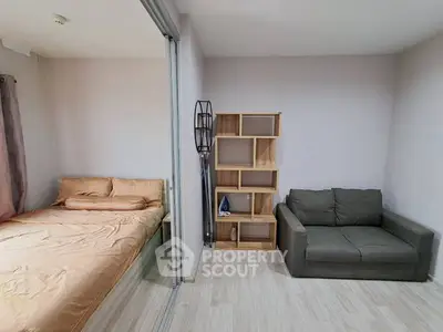 Cozy bedroom with adjacent living area featuring a comfortable sofa and modern shelving unit.