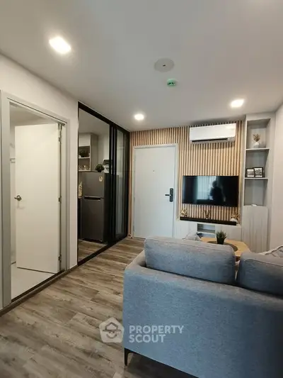 Modern living room with sleek design and open layout, featuring a cozy sofa and wall-mounted TV.