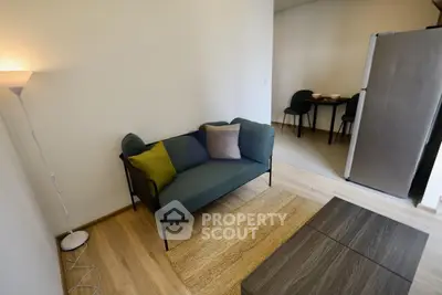 Cozy living room with modern sofa and dining area in open layout apartment.