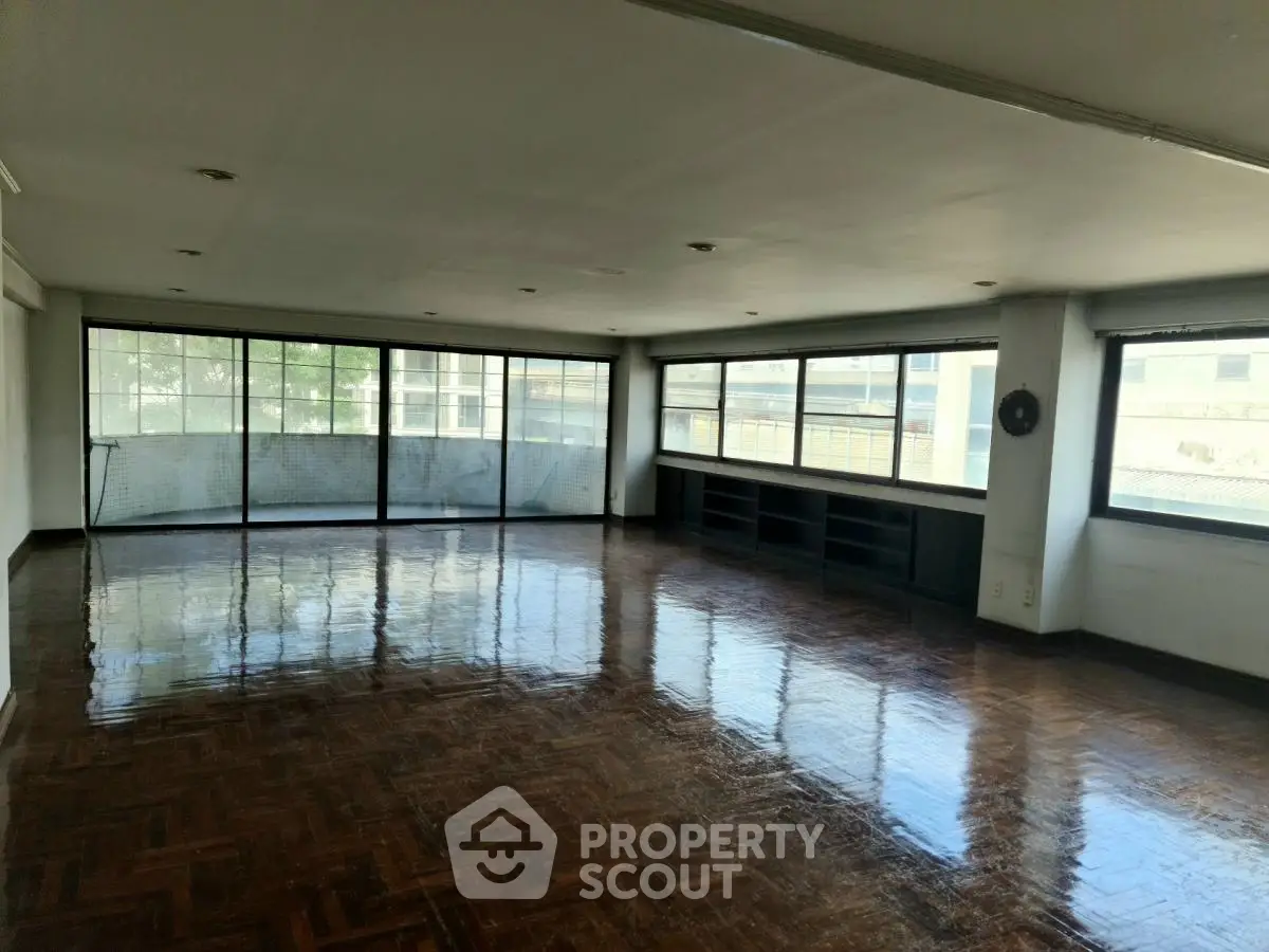 Spacious corner unit with large windows and polished wooden floors, ideal for a bright living room setup.