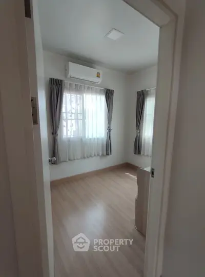 Bright bedroom with air conditioning and wooden flooring, perfect for cozy living.