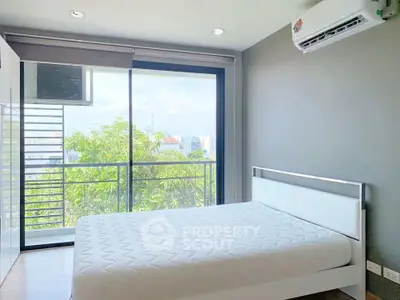 Bright bedroom with large window and balcony view, featuring modern air conditioning unit.